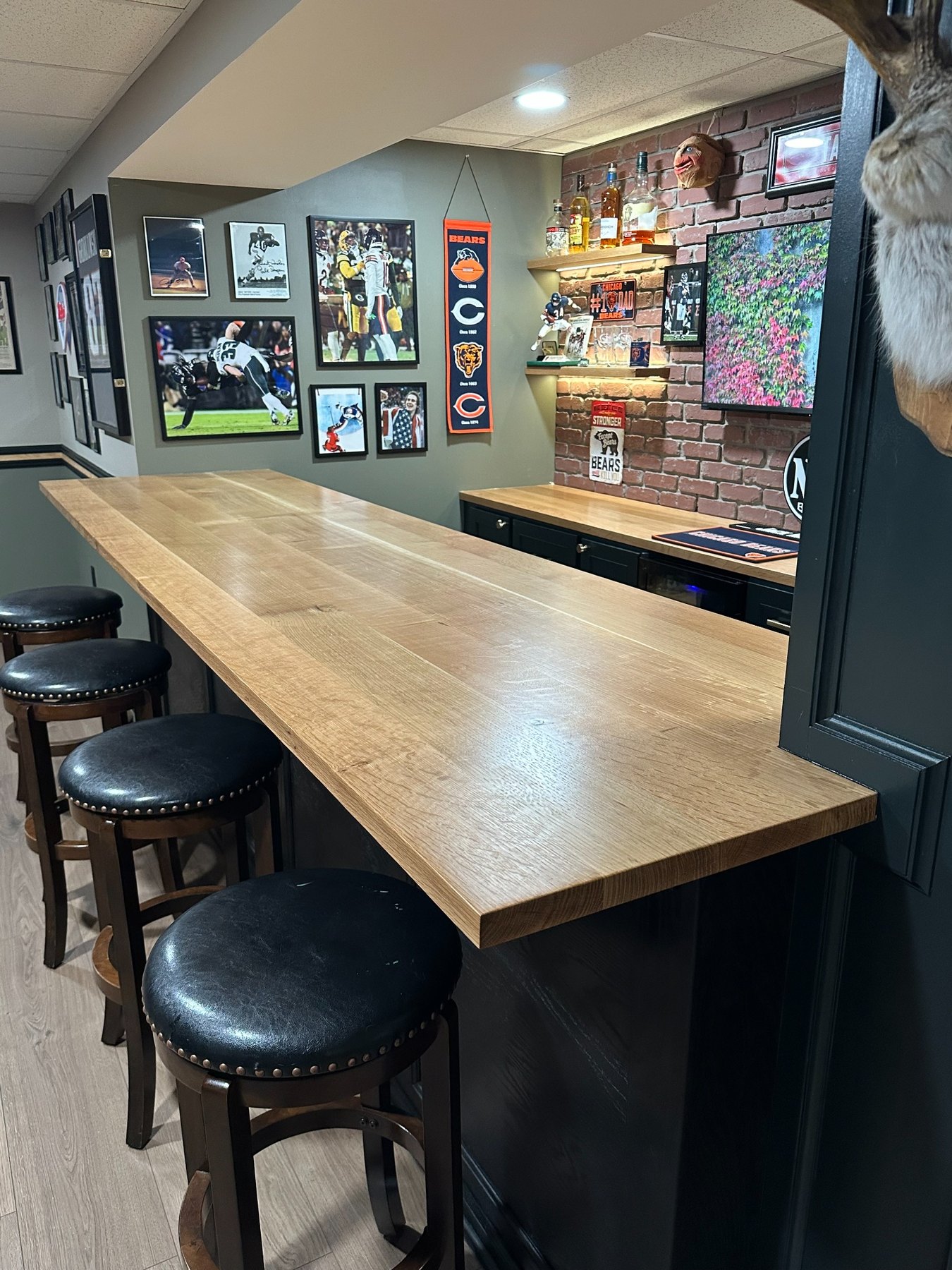 Custom wood bar top with black cabinetry and sports feature wall