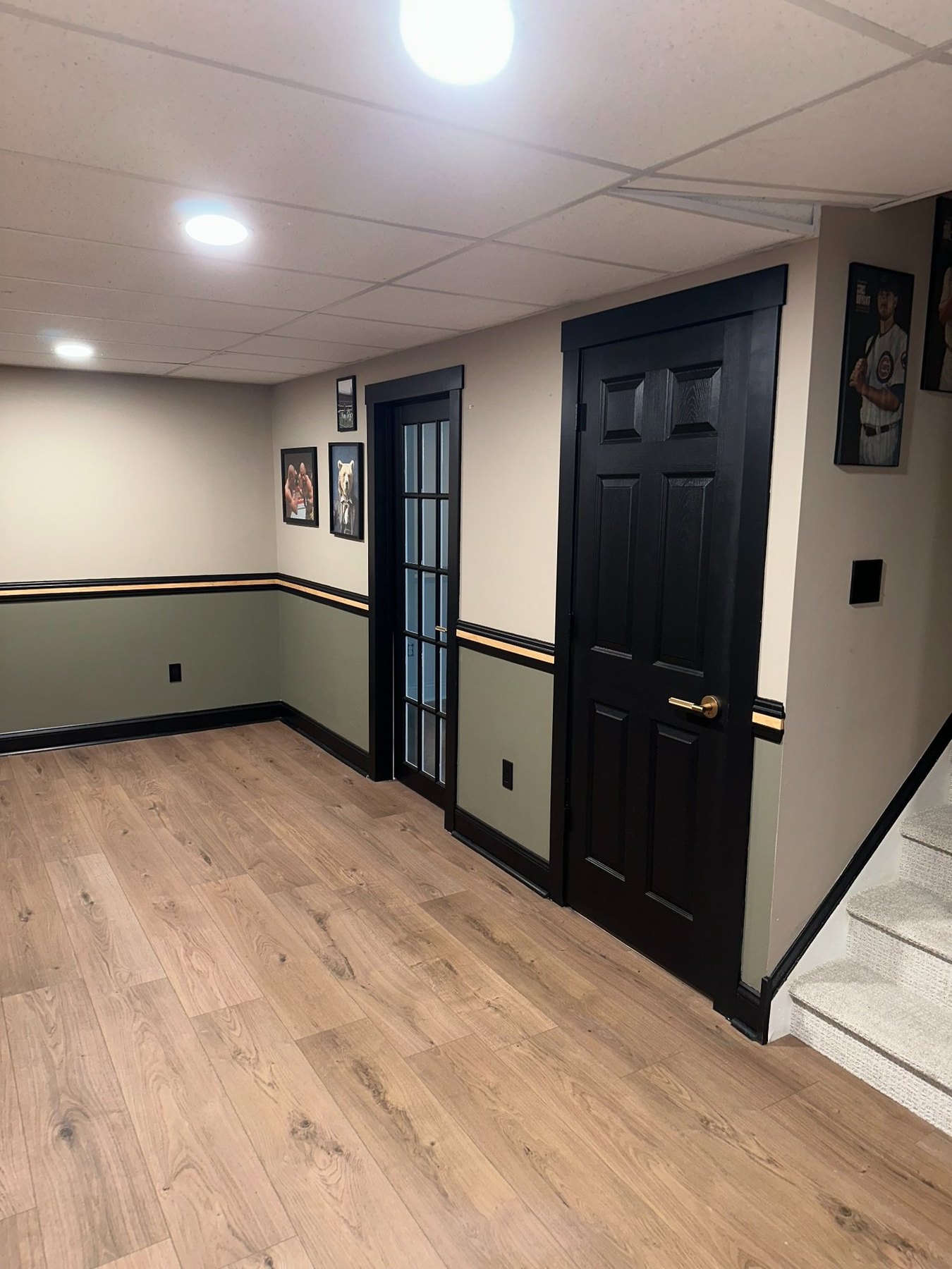 Finished basement hallway with coordinated black doors, trim and wood accent