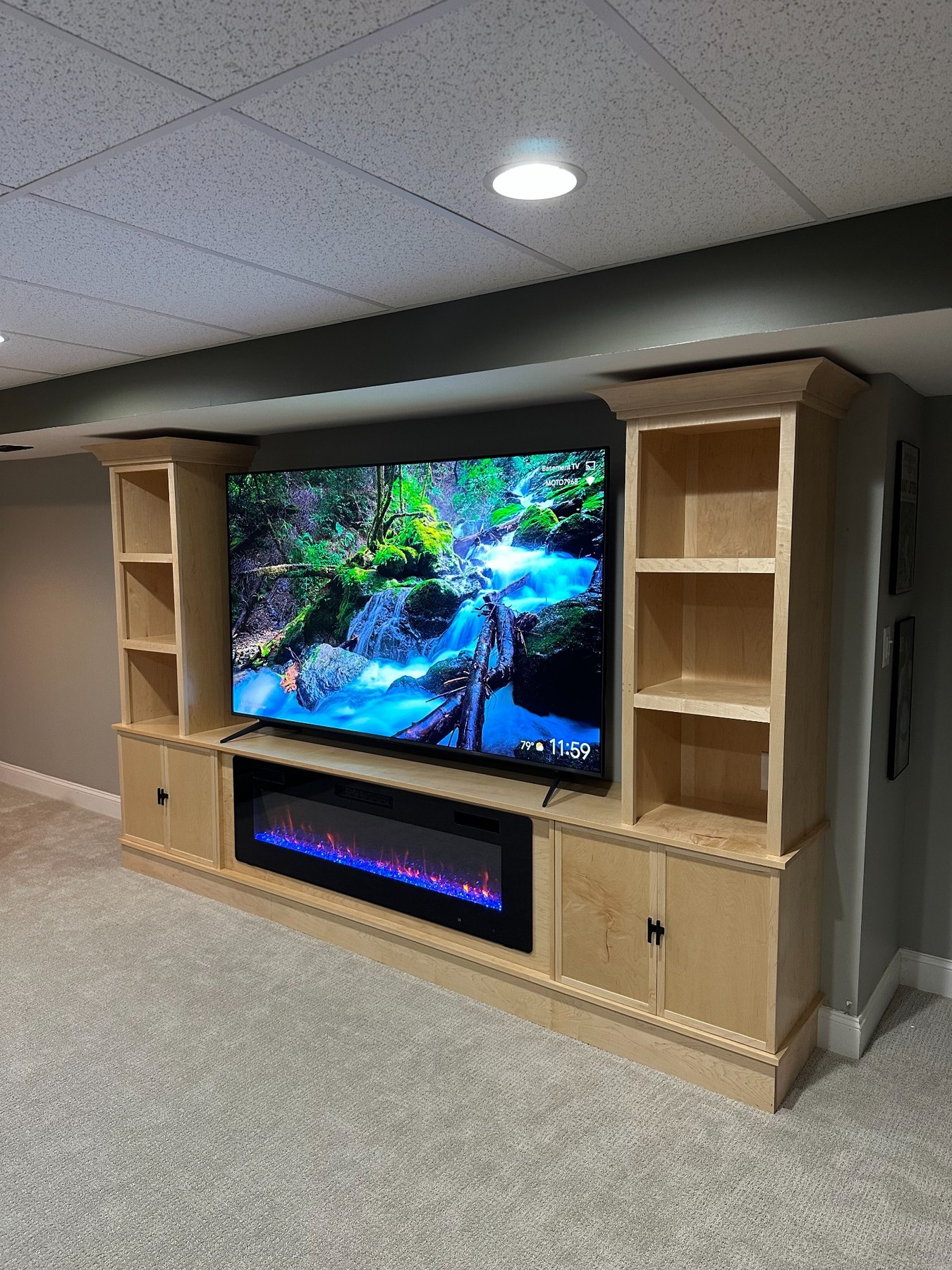 Finished maple entertainment center with television, electric fireplace, shelving and cabinetry