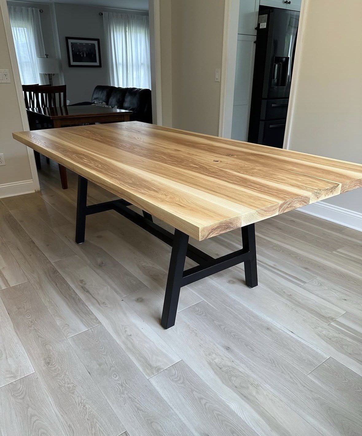 Natural wood dining table with black trestle base