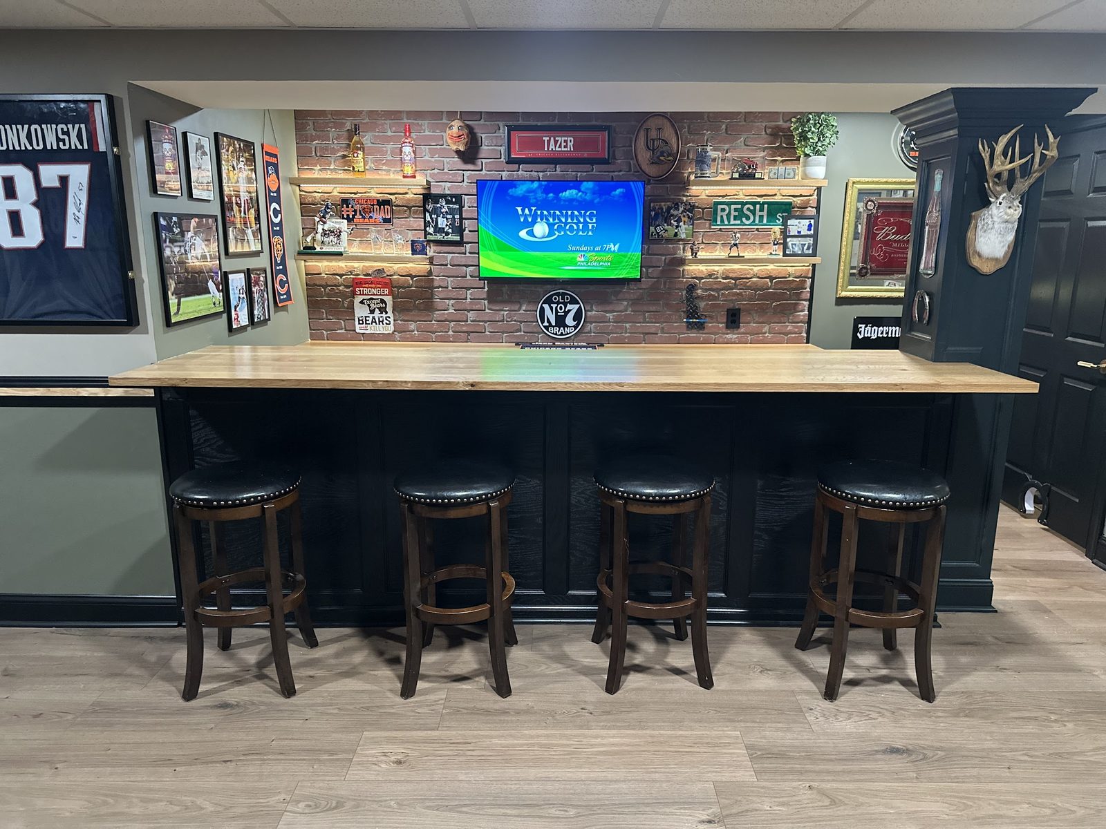 Completed custom basement bar with oak countertop and black cabinetry